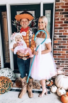 a man and woman dressed up in costumes holding a baby while standing next to each other