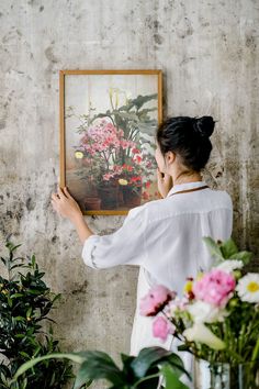 a woman is painting flowers on the wall