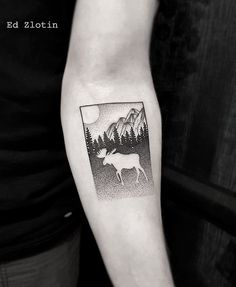 a black and white photo of a deer with mountains in the background tattoo on the left upper arm