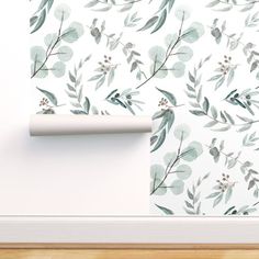 a white wall with green leaves on it and a roll of paper next to it