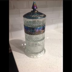 a glass jar sitting on top of a counter next to a white tile backsplash