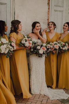 a group of women standing next to each other in front of a white door holding bouquets