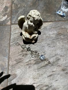 a small angel statue sitting on top of a stone floor next to a chain link