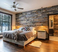 a bedroom with wood paneling and a bed in the middle, next to a large window