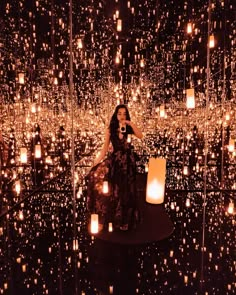 a woman taking a selfie in front of an array of lit up lights and candles