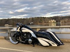 a black and white motorcycle parked on the side of a road next to a body of water