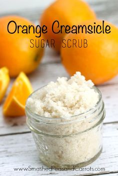 an orange creamsice sugar scrub in a glass jar next to sliced oranges