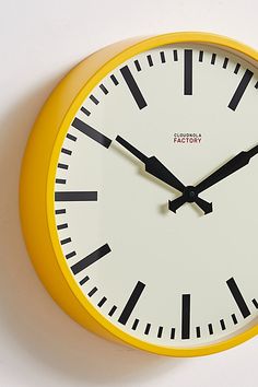 a yellow and black clock on a white wall