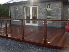 a wooden deck in front of a house with glass doors and railings on it