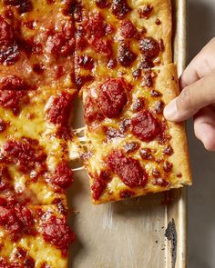 a person picking up a slice of pizza from a pan