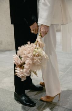 a man and woman holding hands while standing next to each other on the floor in front of a building