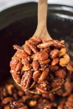 a wooden spoon filled with nuts on top of a table