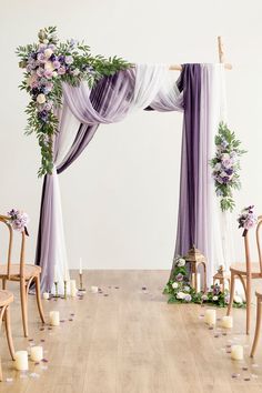 an arch decorated with flowers and greenery for a wedding ceremony in white and purple