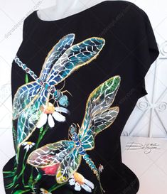 a black t - shirt with dragonflies and daisies painted on it's chest