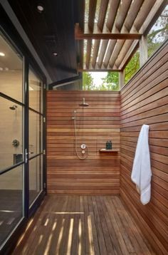 an outdoor shower with wooden flooring and walls