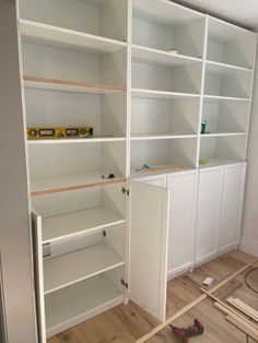 an empty room with white shelves and tools on the floor