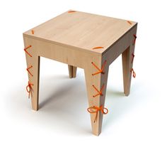 a small wooden stool with an orange string on the legs and bottom part of it