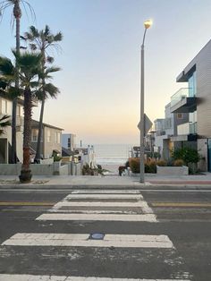 an empty street next to the ocean with palm trees