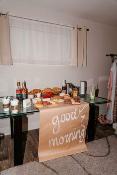 a sign that says good morning next to a table with food and drinks on it