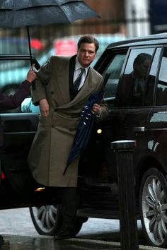 a man holding an umbrella next to a car