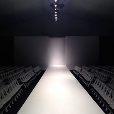 an empty runway with rows of chairs in front of it and a light at the end