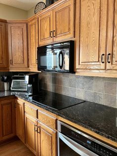 a kitchen with wooden cabinets and black granite counter tops, stainless steel appliance