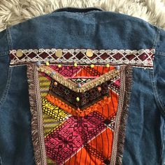 the back of a jean jacket with an embroidered patchwork design and beaded details