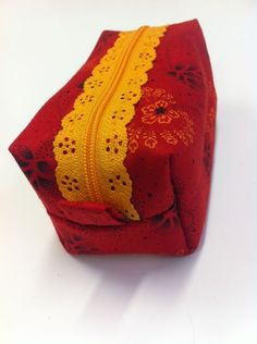 a red and yellow purse with lace on the inside is sitting on a white surface