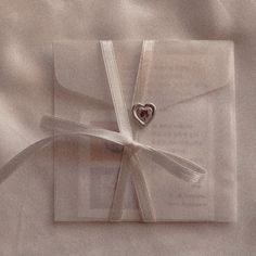 an open book with a heart on the cover and ribbon tied around it, laying on a bed sheet