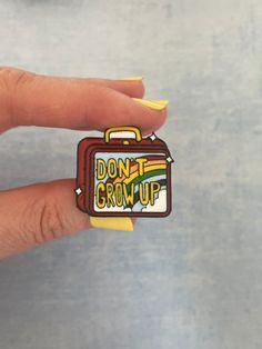 a woman's hand holding a piece of sticker with the words don't grow up on it