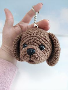 a hand holding a brown crocheted dog keychain