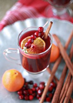 a glass mug filled with cranberry orange punch and cinnamon stick garnish