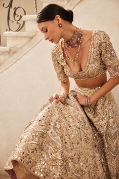 a woman in a gold dress sitting on the stairs with her hand on her hip