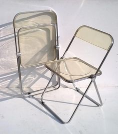 two folding chairs sitting next to each other on a white floor with no one in it