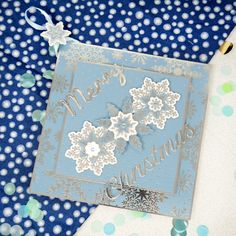 a blue and white christmas card with snowflakes on it, surrounded by confetti