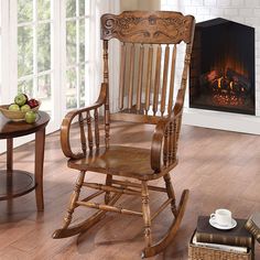 a wooden rocking chair sitting on top of a hard wood floor next to a fire place