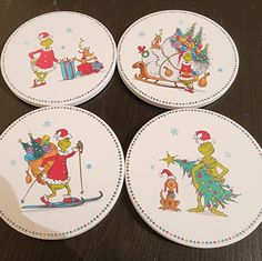 four plates with cartoon characters on them sitting on a wooden table, one has a santa hat and the other has a christmas tree