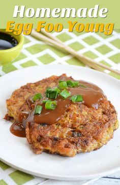 an egg foo young on a plate with sauce and chopsticks next to it