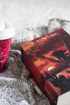 a harry potter book next to a cup of coffee on a bed with a blanket