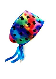 a tie dye dog hat with paw prints on the front and blue ribbon at the bottom