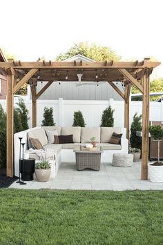 an outdoor living area with couches, tables and potted plants on the grass