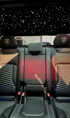 the interior of a sports car with black leather seats and star lights on the ceiling