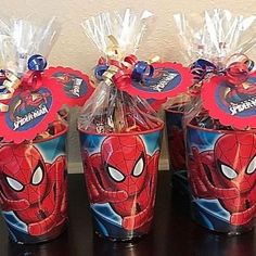 three plastic cups with spiderman candy wrappers in them sitting on a table next to each other