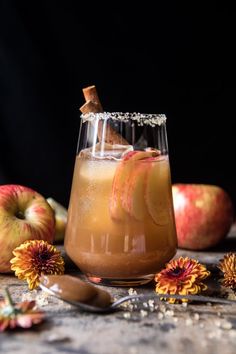 an apple cider cocktail is garnished with cinnamon and apples