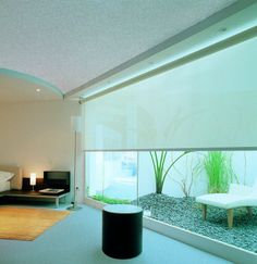 a living room filled with furniture next to a window covered in plants and graveled ground