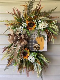 a fall wreath with pumpkins, sunflowers and other flowers on the front door