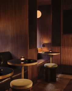 two tables and stools in a room with wood paneling