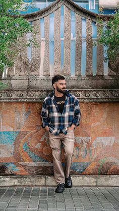 a man standing in front of a building with graffiti on the wall and his hands in his pockets