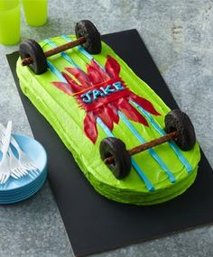 a cake shaped like a race car on top of a table with plates and forks