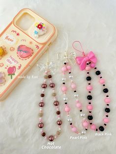 three necklaces and a cell phone case on a white furnishing with hello kitty charms